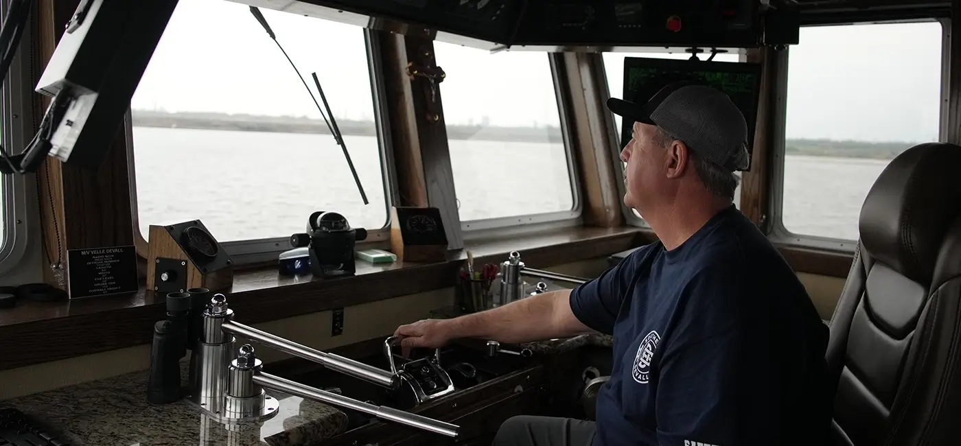 A Southern Devall Barge captain manning the helm of a tow boat