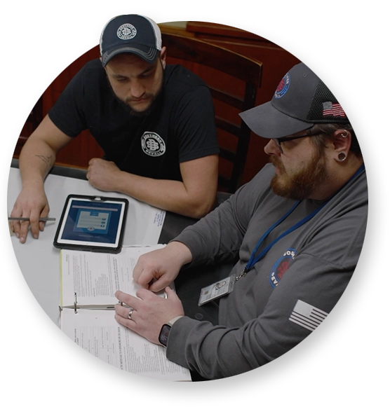 Two Southern Devall crewmen reviewing safety documents in a binder and on a tablet