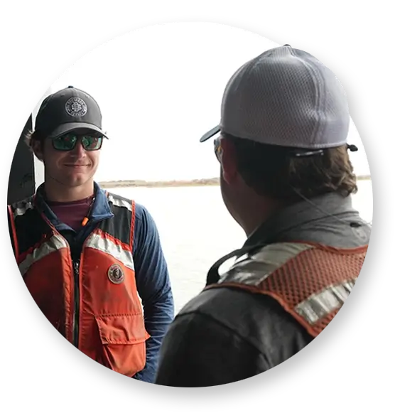 Two Southern Devall crewman in life vests talking on the deck of a ship